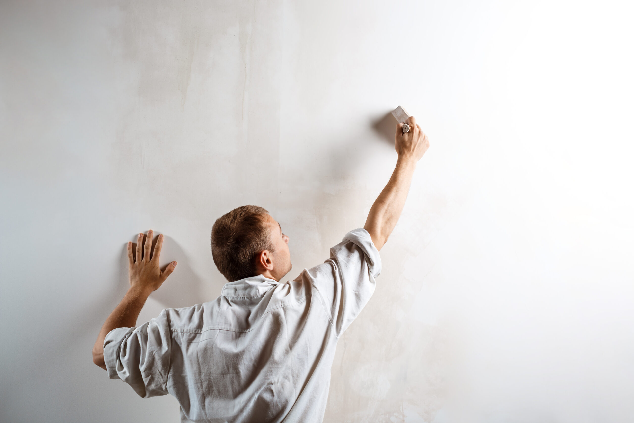 Professional worker painting wall with brush in white color. Copy space.